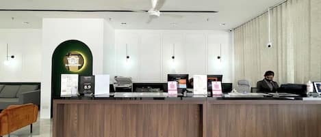 A reception desk with a modern design, a green archway, and a ceiling fan.