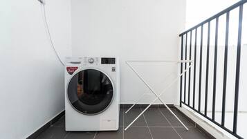 Una unitat rentadora i seca compacta en una cantonada d'una habitació amb terra de rajola i barana de metall negre.