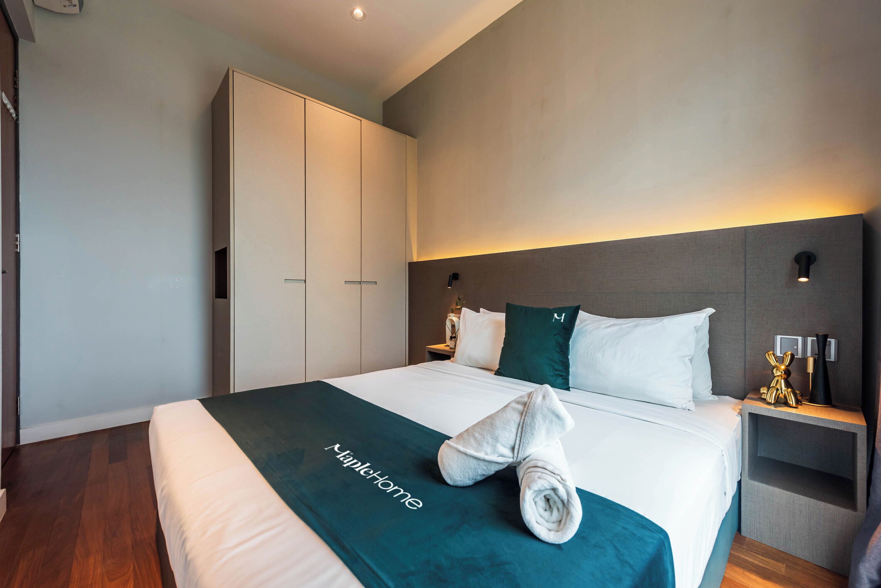 A hotel room with a large bed, a wardrobe, and a nightstand with a lamp.