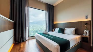 A hotel room with a large bed, a nightstand, a wall-mounted light, and a view of a mountainous landscape.