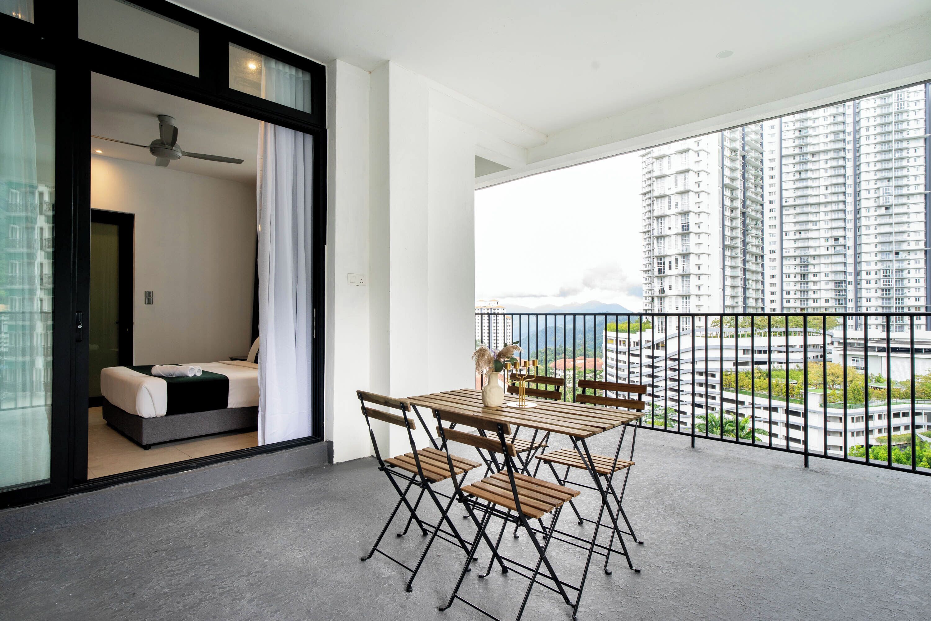 A balcony with a table and chairs, a sofa, and a view of high-rise buildings.