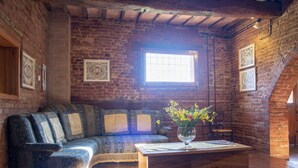 A cozy room with a wooden bench, a sofa with patterned cushions, and a wooden coffee table with a vase of flowers.