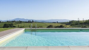 A swimming pool with a clear view of the surrounding landscape, including hills and distant mountains.