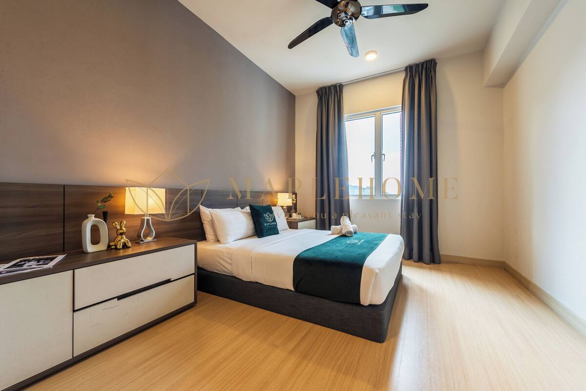 Une chambre d’hôtel moderne équipée d’un lit, de tables de chevet, d’un ventilateur de plafond et d’une grande fenêtre avec des rideaux.
