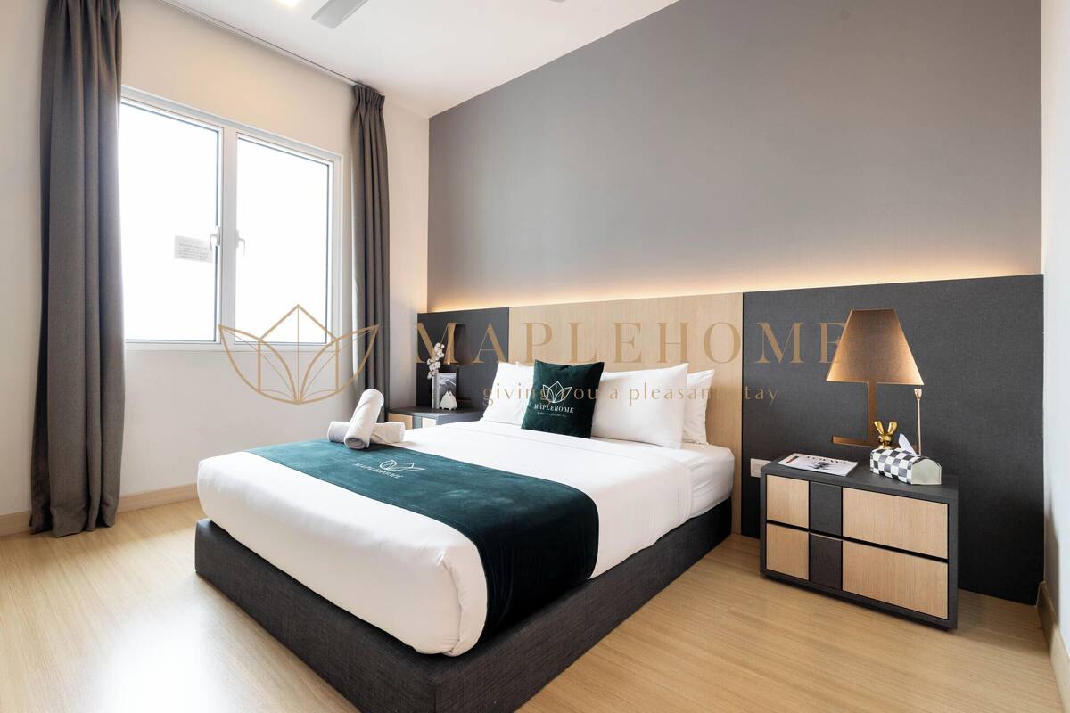 Une chambre d’hôtel moderne avec un grand lit, une table de chevet avec une lampe et une vue sur la ville par la fenêtre.