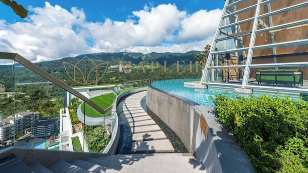 Un hotel moderno con piscina, una escalera que lleva a una terraza en la azotea y vistas a montañas al fondo.
