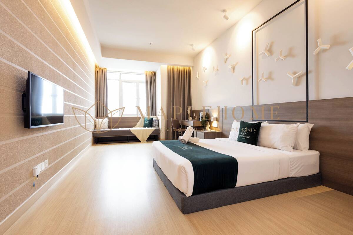 Une chambre d’hôtel moderne dotée d’un grand lit, d’un téléviseur à écran plat, d’un bureau et d’un coin salon avec une chaise et une petite table.