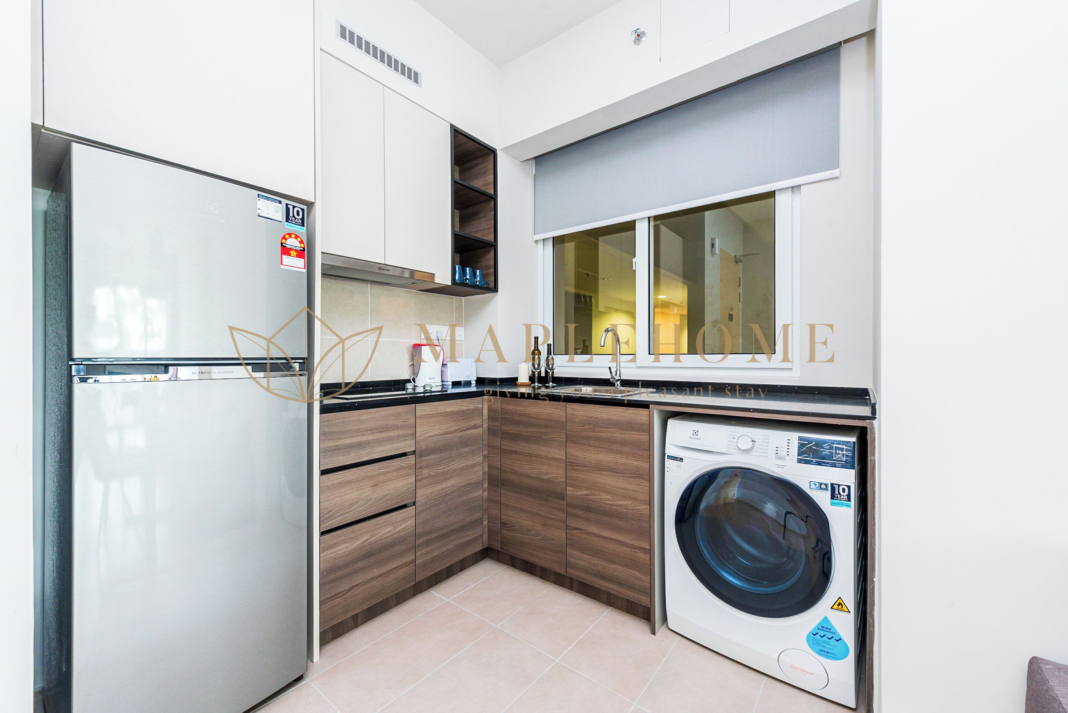 A modern kitchen with a built-in washing machine, wooden cabinets, and a stainless steel refrigerator.