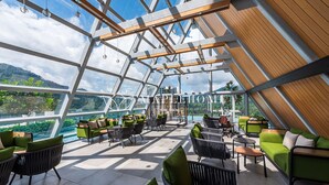 Un amplio salón al aire libre con mobiliario moderno y vistas a las montañas.