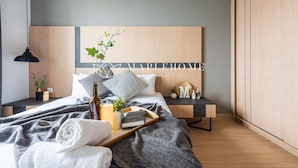 Un dormitorio moderno con cama, mesitas de noche, una lámpara, una planta en maceta y un cartel en la pared.