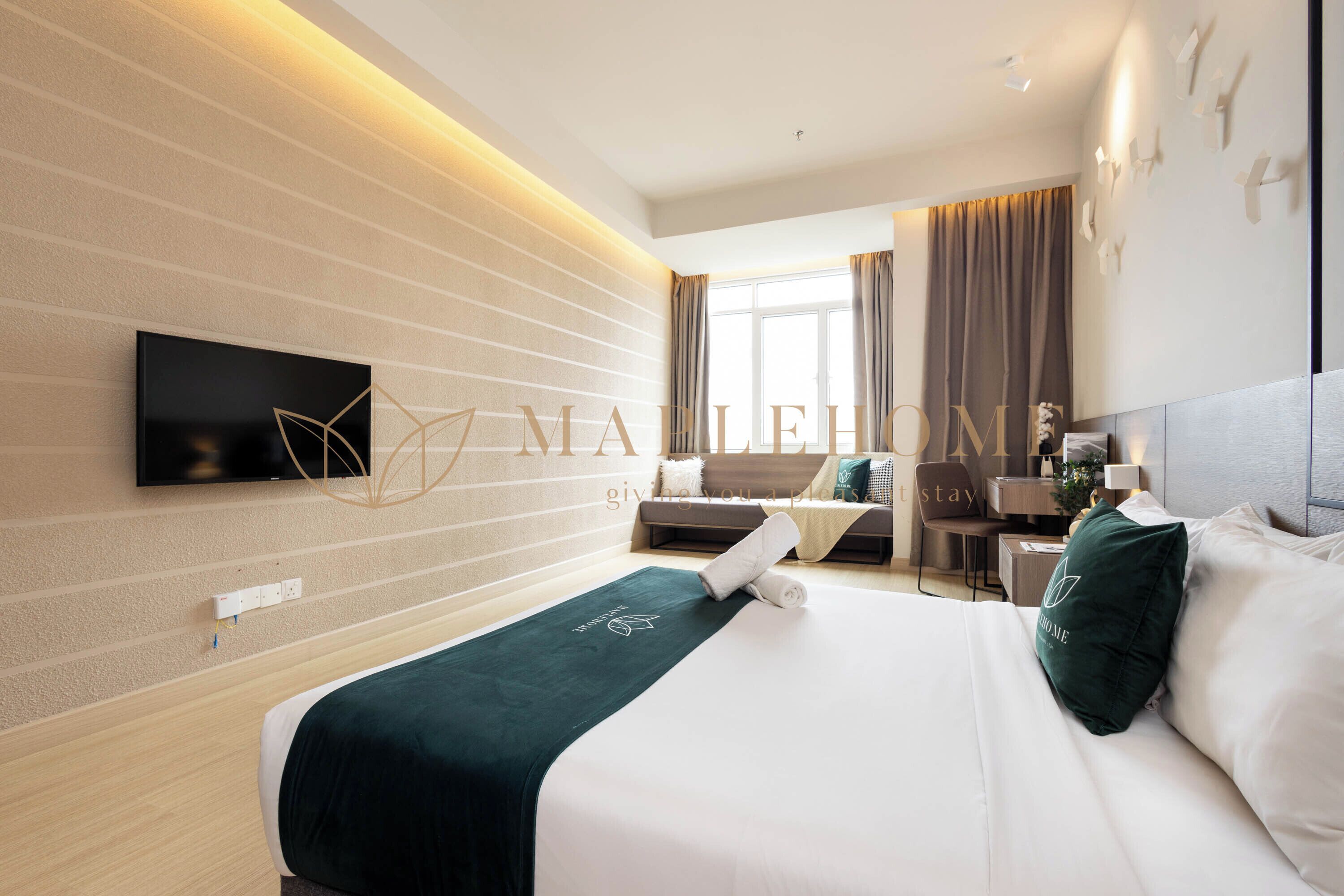 A modern hotel room with a bed, a desk, and a television mounted on the wall.