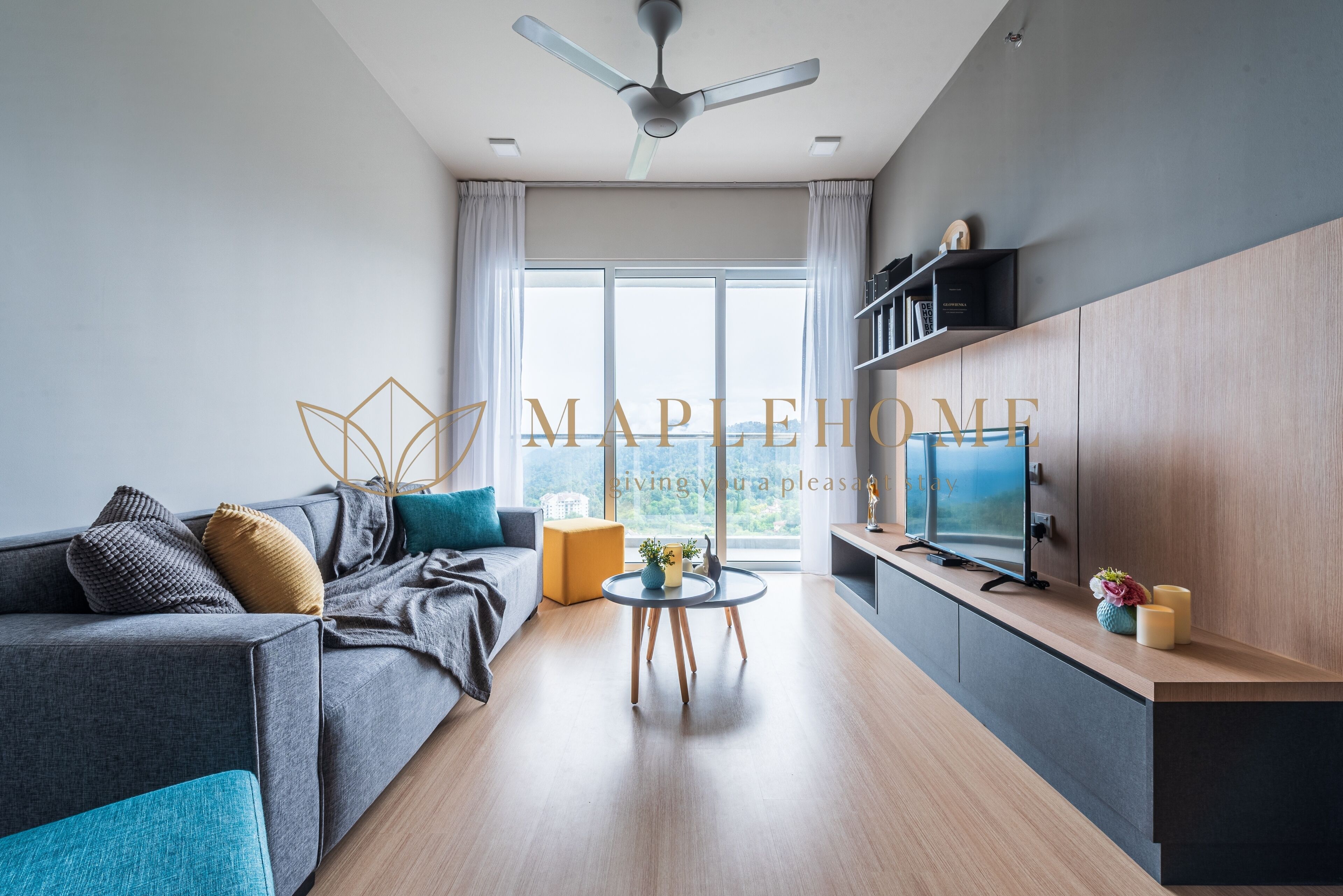 A modern living room with a grey sofa, a small round table, and a TV on a wooden cabinet.