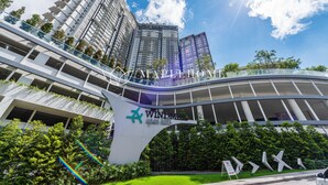 Un hotel moderno con una entrada curva distintiva, varios pisos y abundante vegetación.
