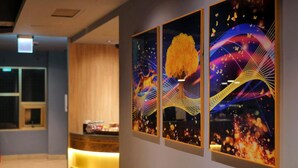 A hotel reception area with a wooden reception desk and three framed artworks on the wall. - Modern Inn (Taichung)