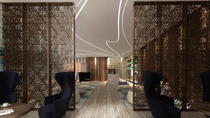 A modern hotel lobby with a marble floor, dark upholstered chairs, and a central reception desk. - Jouri A Murwab Hotel (Doha)