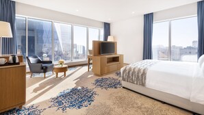 A modern hotel room with a large bed, a TV, a desk with a lamp, and a view of the city. - Jouri A Murwab Hotel (Doha)