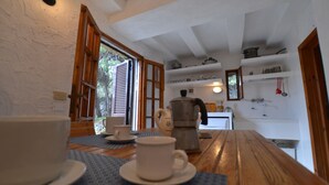 A cozy kitchen with wooden tables, white walls, and a window with open shutters. - Romantic trullo with sea access and stunning views (house G) (Castro)