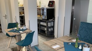 Un espace repas moderne avec des chaises de couleur turquoise, une table en bois et, au fond, un coin cuisine.