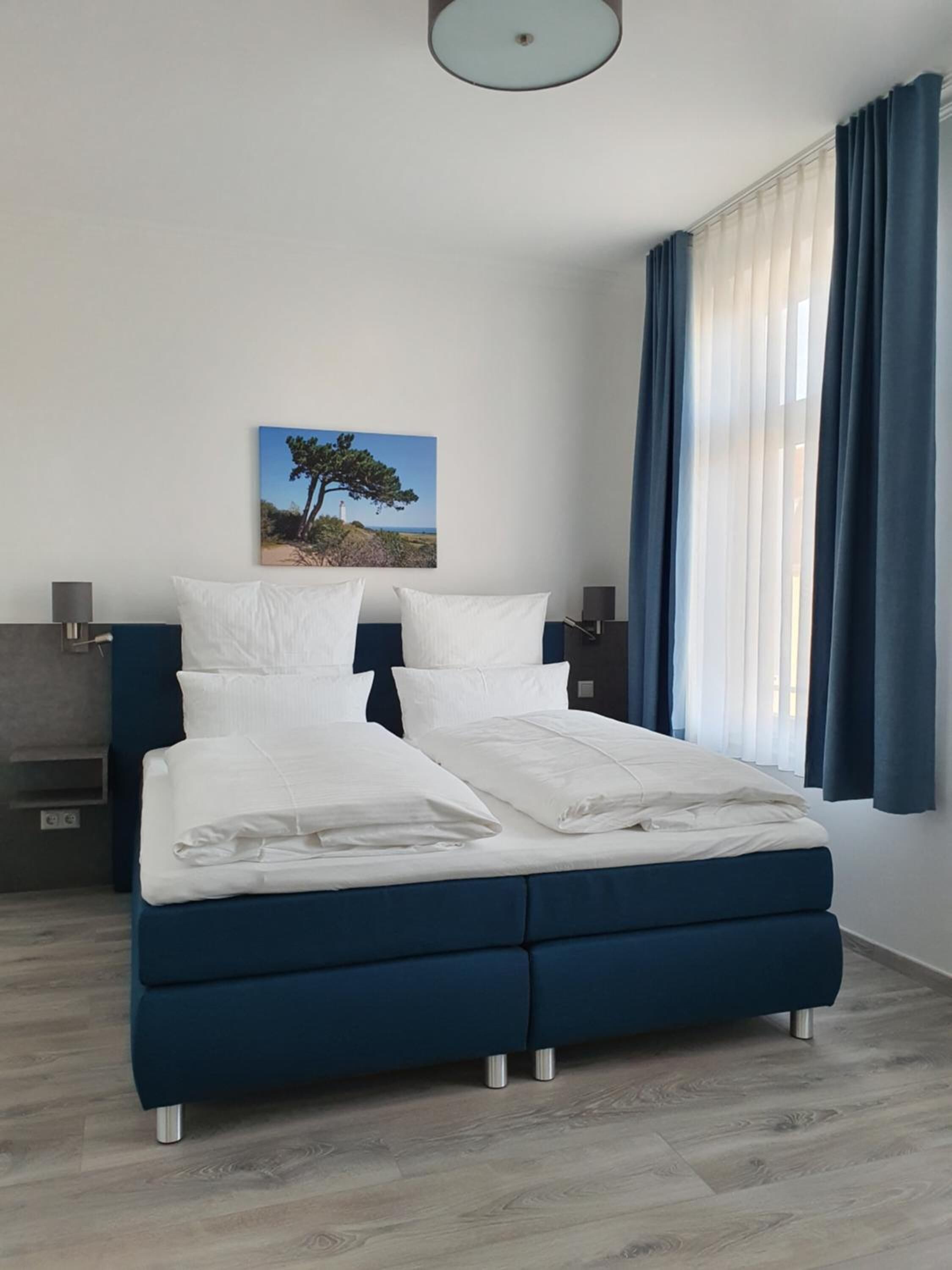 Una camera da letto moderna con un letto grande, un comodino, una lampada e un quadro appeso al muro.