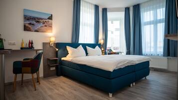 Une chambre d’hôtel moderne dotée d’un grand lit, d’un bureau avec une chaise et offrant une vue sur la plage par la fenêtre.