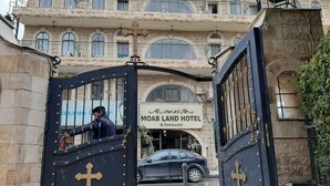 A hotel entrance with a large gate, a sign reading "MOAB LAND HOTEL & Restaurant," and a car parked in front.