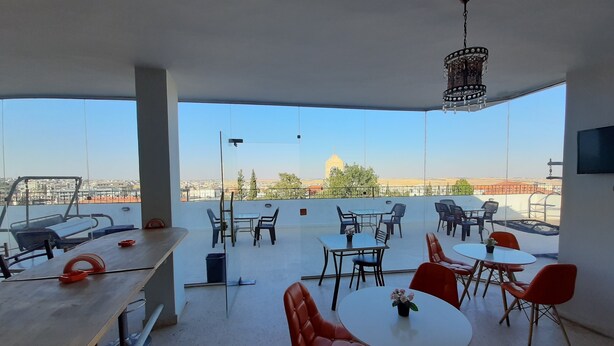 Una terraza en la azotea con mesas y sillas, una cinta de correr y vistas de la ciudad.