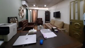 Una sala de estar con un sofá, una mesa de centro, una computadora portátil y un televisor.