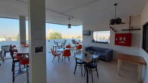 Un comedor amplio con mesas y sillas altas, un sofá y una manguera contra incendios en la pared.