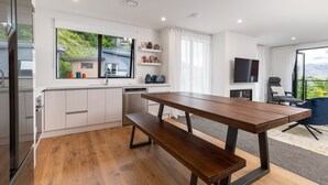 A modern kitchen with white cabinets, a wooden bench, and a large window overlooking a house. - MyHolidays - The Four Seasons Queenstown (4 brms + 4.5 bathrooms) (Queenstown)
