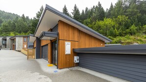 A row of modern cabins with wooden exteriors and grey roofs, set against a forest backdrop. - MyHolidays - The Four Seasons Queenstown (4 brms + 4.5 bathrooms) (Queenstown)