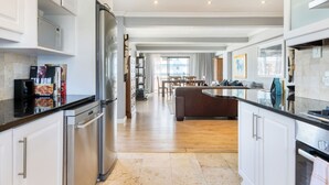 Una cocina moderna con electrodomésticos de acero inoxidable, un comedor con mesa y sillas de madera, y vistas al exterior.