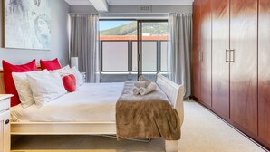 Ein Hotelzimmer mit Bett, großem Kleiderschrank, einem Gemälde an der Wand und Blick ins Freie.