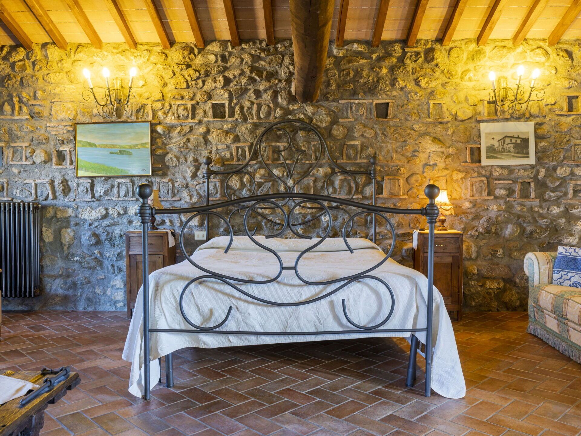 A stone-walled bedroom with a bed, a radiator, and a wooden floor.