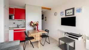 A compact living space with a kitchenette, dining area, and a TV mounted on the wall.