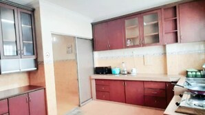 A compact kitchen with wooden cabinets, a refrigerator, and a stove. - Hotel Sri Bahau (Bahau)