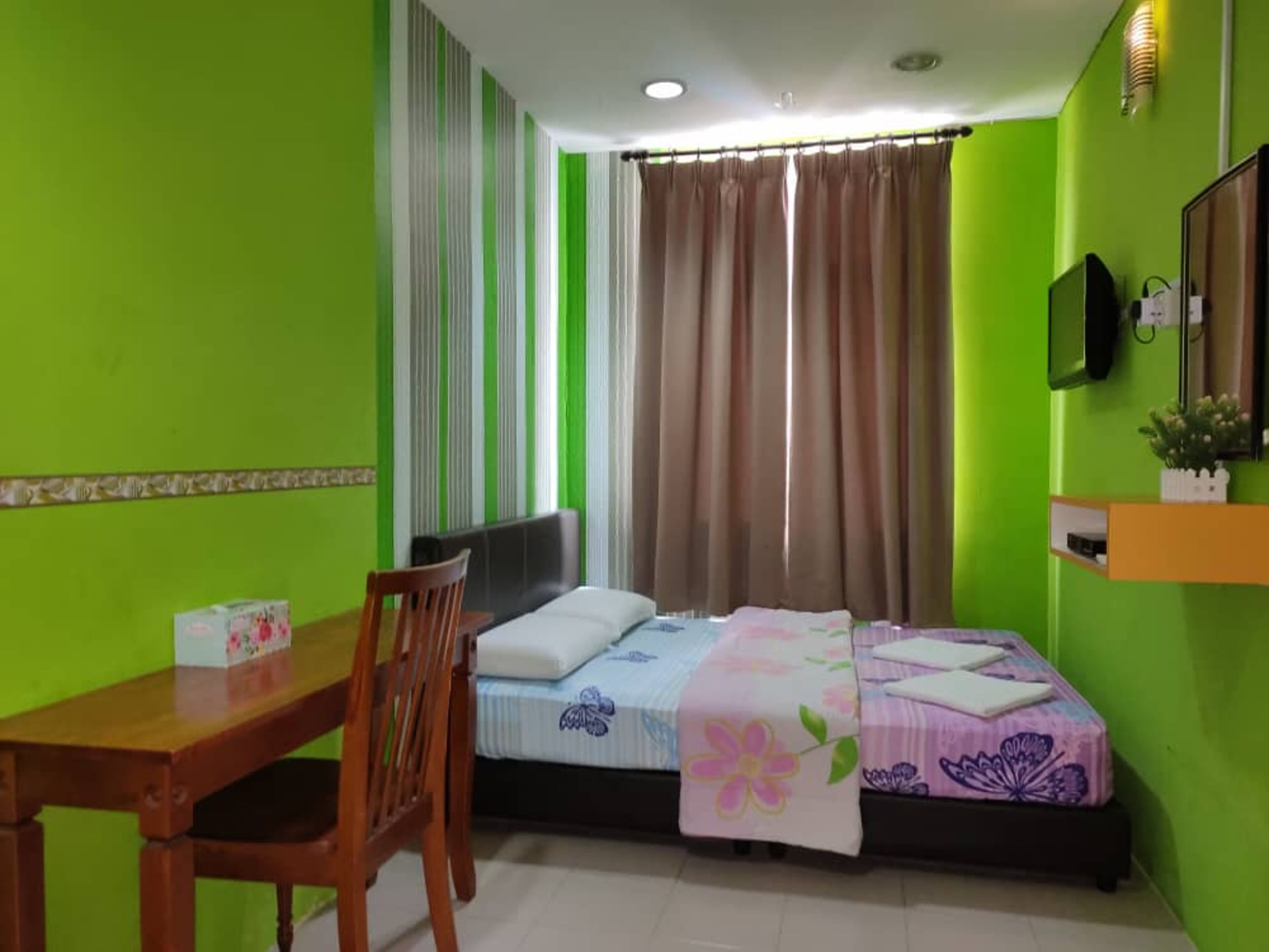 A small, brightly colored room with a bed, a desk, and a chair.