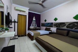 A hotel room with a bed, a desk, a chair, a television, and a window with purple curtains. - Hotel Sri Bahau (Bahau)