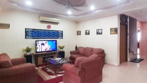 A living room with a flat-screen TV, two red sofas, a coffee table, and a decorative wall piece. - Hotel Sri Bahau (Bahau)