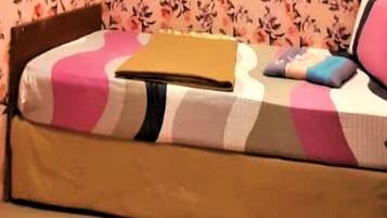A small, cozy room with a bed, a nightstand, and a wall with floral wallpaper.