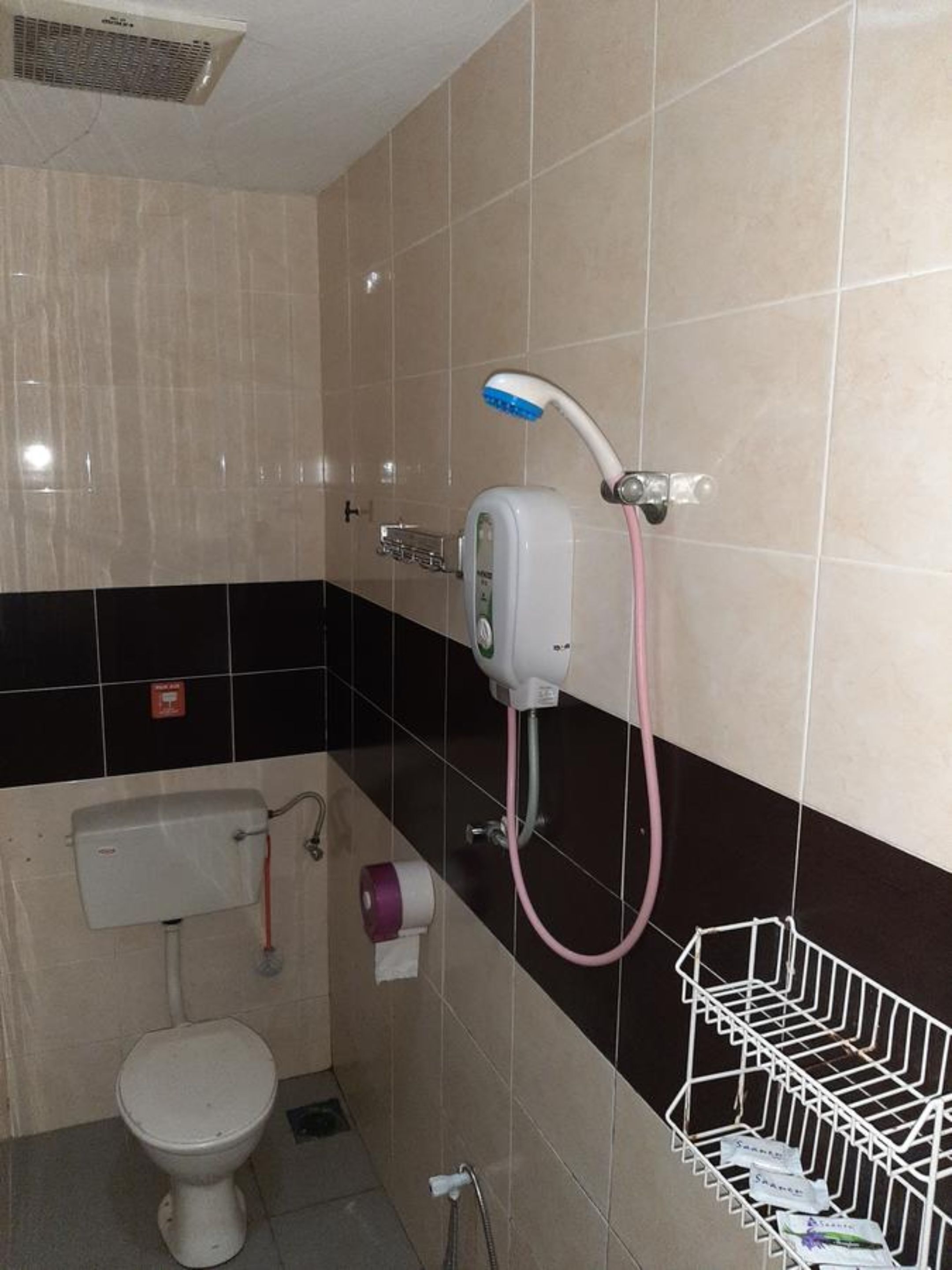 A bathroom with a toilet, a sink, a shower with a handheld showerhead, and a towel rack.