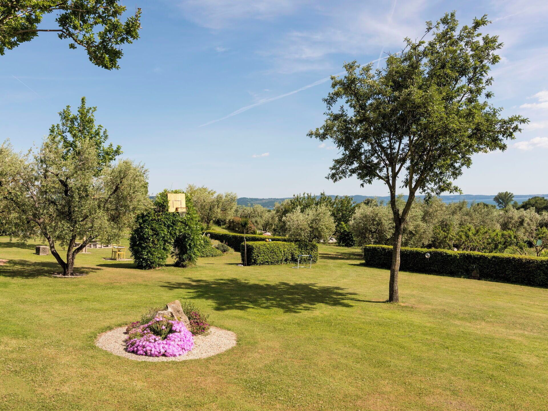 A well-maintained garden with a variety of trees and a circular flower bed.