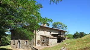 Une maison en pierre avec un toit en pente, un petit porche et un escalier en pierre menant à l’entrée.