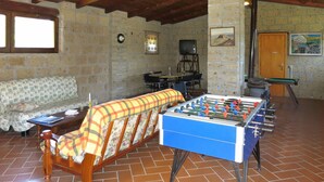 Une pièce confortable avec un canapé, un baby-foot, une télévision et un piano.