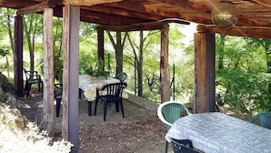An outdoor wooden pergola with tables and chairs, surrounded by trees. - Lovely apartment in villa for 5 people with WIFI, pool and patio (Vaiano)