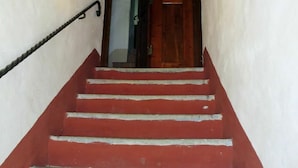 A staircase with red steps leading to a wooden door, under a tiled archway. - Lovely apartment in villa for 5 people with WIFI, pool and patio (Vaiano)