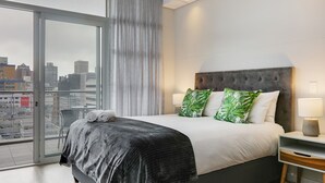 Une chambre d’hôtel moderne avec un grand lit, une vue sur la ville et un balcon.