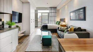 Une chambre d’hôtel moderne équipée d’un lit, d’un canapé, d’une table à manger et d’un téléviseur.
