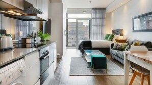 Une chambre d’hôtel moderne dotée d’une kitchenette, d’un lit avec vue, d’un canapé et d’un coin repas.