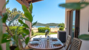 Una mesa de madera preparada para dos personas, con vistas al mar y a las colinas.