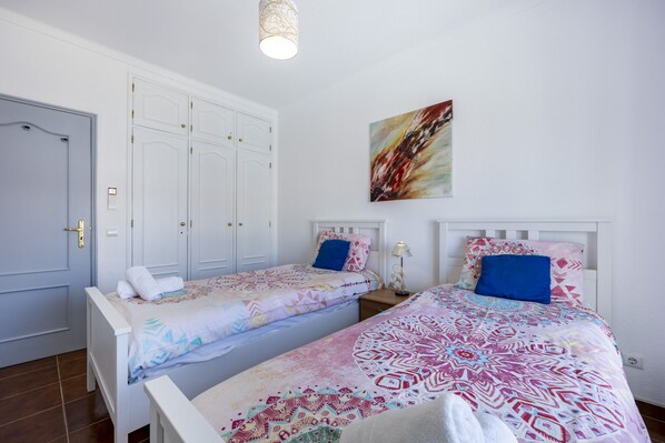 A room with two beds, a wardrobe, and a painting on the wall.